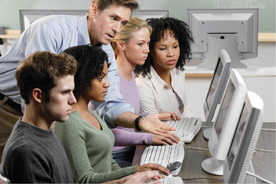 Picture of Students Using Computers and Receiving Instruction from Facilitator